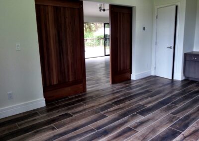 An empty room with wooden flooring, featuring sliding doors on one wall and a white door on another.