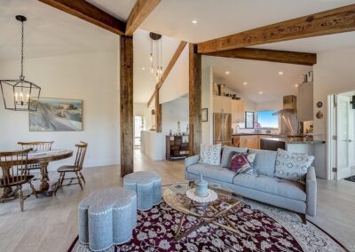 Modern living room with open plan kitchen, exposed beams, and coastal decor.