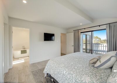 Bright bedroom with a large bed, sliding glass door, and an attached bathroom.