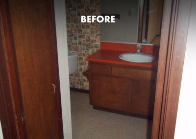 Before renovation: an outdated bathroom with wooden vanity and patterned wall tiles.